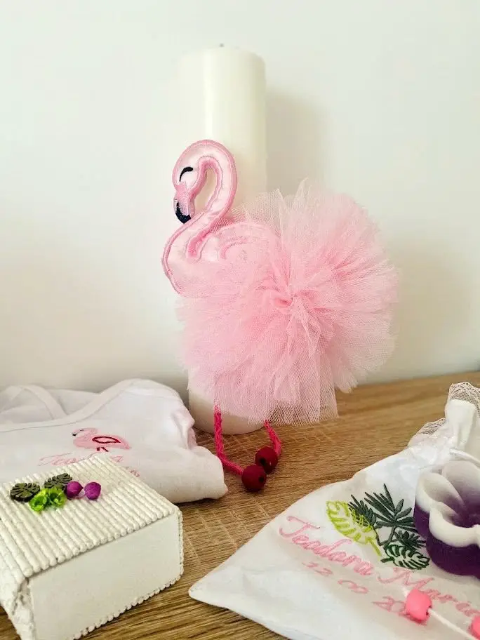 Lumânare de botez decorată cu un flamingo roz și tul pufos, alături de accesorii brodate