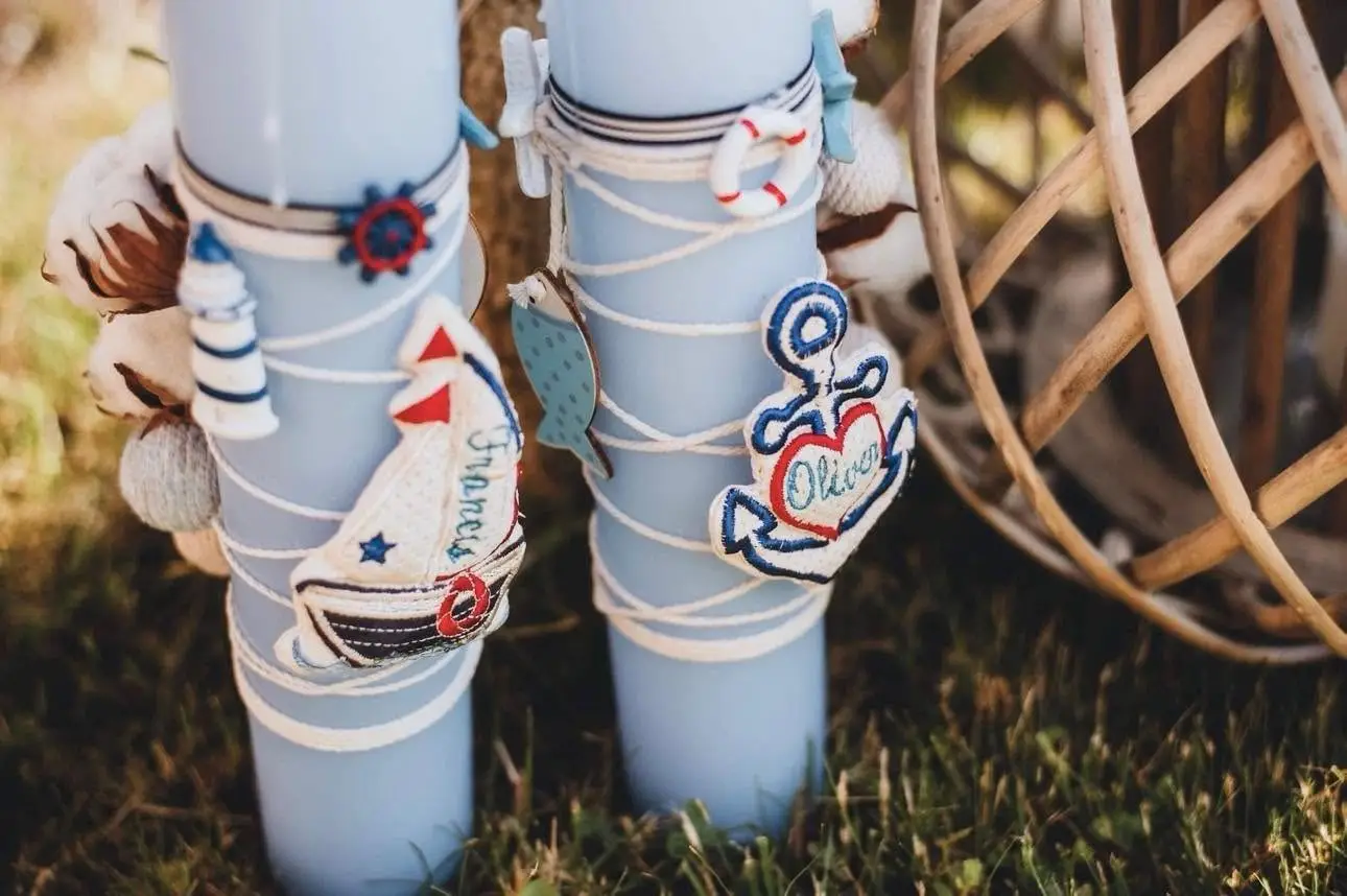 Două lumânări de botez bleu decorate cu bărcuțe, ancore și colaci de salvare
