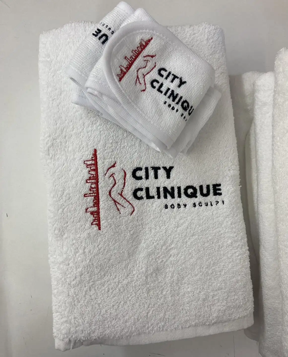 Prosoape și benzi de păr albe brodate cu logo-ul unui salon de remodelare corporală