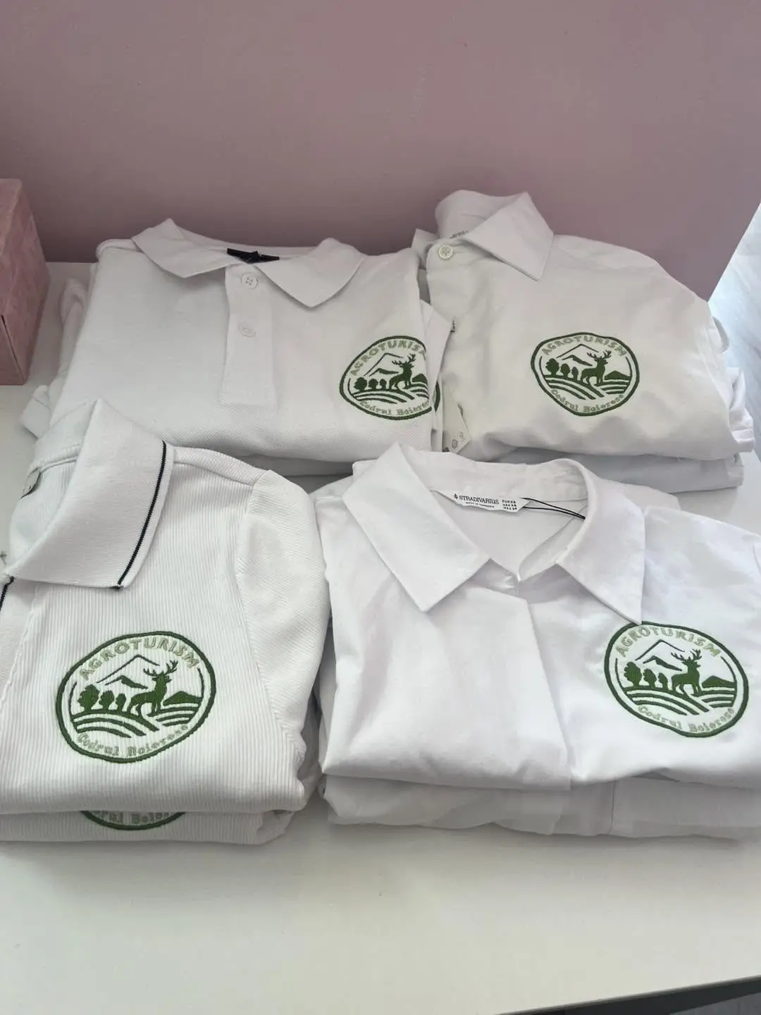 Tricouri polo albe brodate cu logo-ul verde al unei pensiuni agroturistice